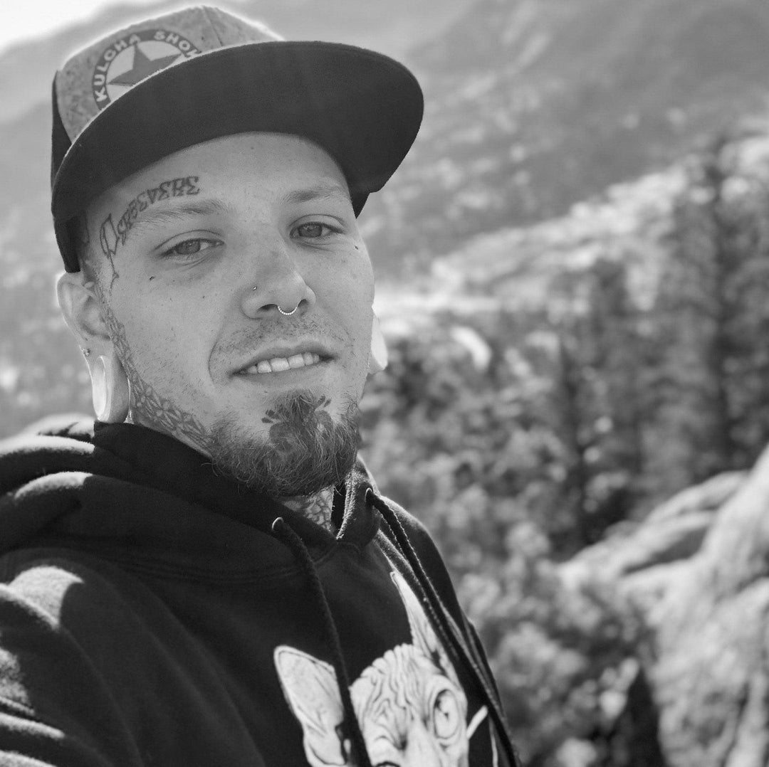 Tattooed man outdoors in New York, wearing FYT Tattoo Supplies hoodie and cap