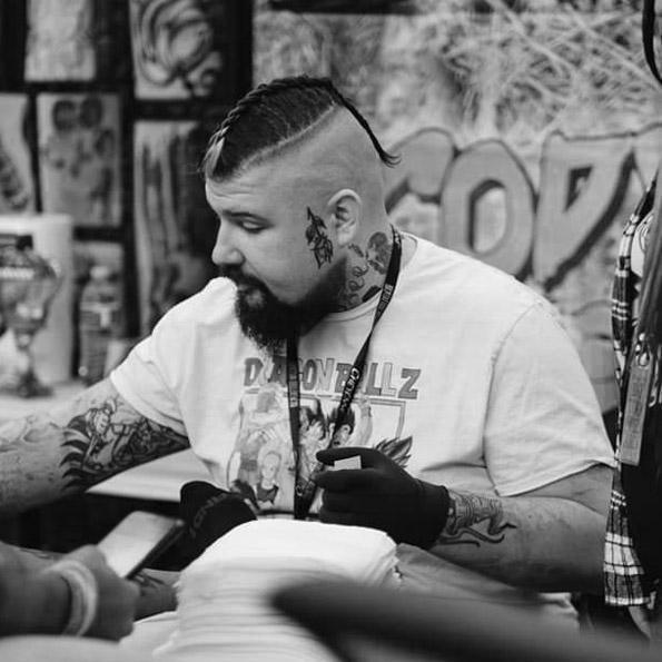 Tattoo artist with face and arm tattoos using FYT tattoo supplies in New York studio
