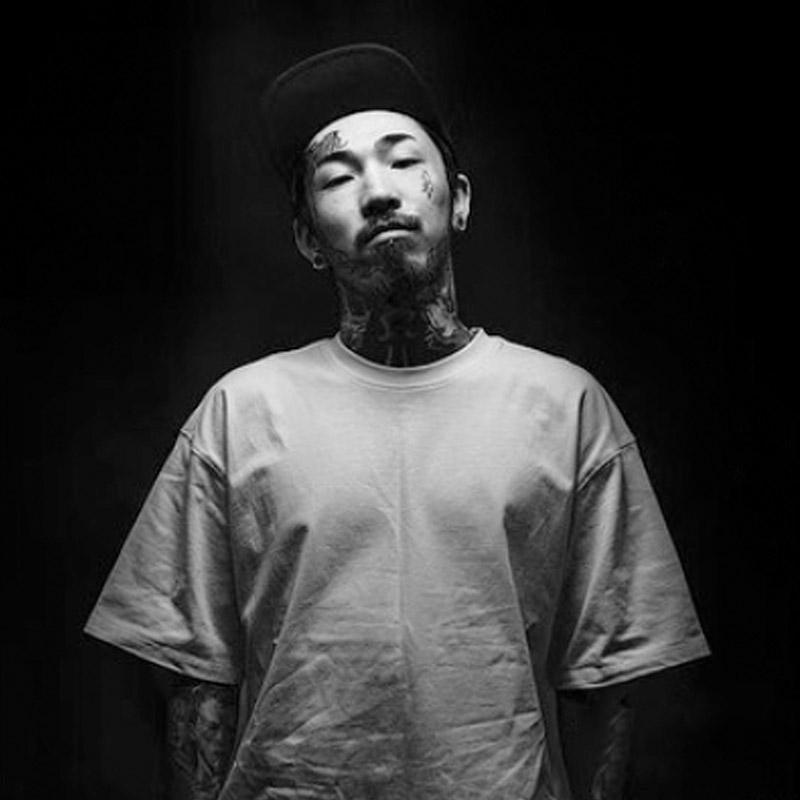 Tattooed man in white shirt and cap, FYT Tattoo Supplies New York black background portrait